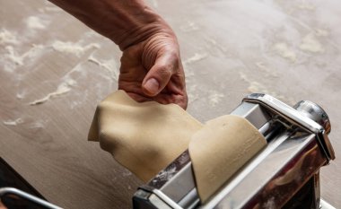 Makarna makinesi. Taze makarna, ev yapımı. Erkek el hamur fileto yapıyor. Yakın görüş.