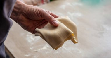 İnce hamur işleriyle el ele tutuşup, manzarayı kapatıyoruz. Ev yapımı turta yapmak, pişirmek. Bulanık arkaplan, boşluğu kopyala