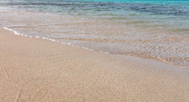 Yunanistan 'da kumlu bir sahil, manzarayı kapat. Deniz suyu ıslak beyaz kuma dokunur, yukarıdan görünür, uzayı taklit eder. Güneşli bir gün, yaz tatili, Yunan adası.