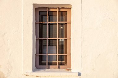 Beyaz arka planda eski pencere ve tırabzan metal parmaklıklar var. Ev güvenliği, ön manzara. Yunanistan 'da geleneksel mimari
