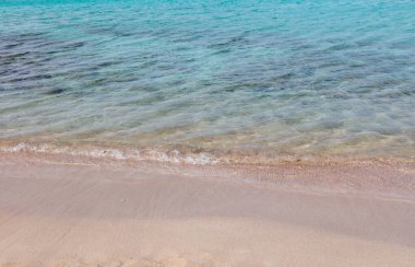 Yunanistan 'da kumlu bir sahil, manzarayı kapat. Deniz suyu ıslak beyaz kuma dokunur, yukarıdan görünür, uzayı taklit eder. Güneşli bir gün, yaz tatili, Yunan adası.