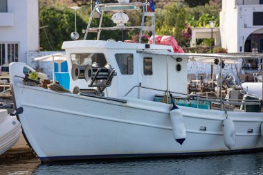 Kythnos adası Loutra limanına demir atmış bir balıkçı teknesi. Geleneksel ahşap gemi. Görüntü liman binalarının arka planı. Güneşli yaz günü
