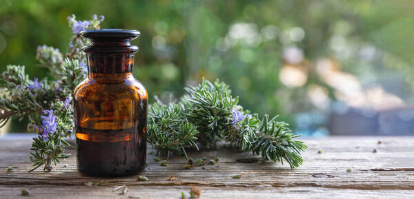 Lavender essential oil glass bottle on wooden table, close up view. Aromatherapy blooming herb, copy space, blur nature background