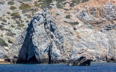 Ege Denizi. Kaya oluşumları, kayalıklar ve mağaralar, dalgalı okyanus suları. Kiklad Yunanistan. Ios adası yakınlarında deniz manzarası, güneşli de
