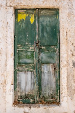 Yeşil ahşap eski kapalı kapı, ön manzara. Terk edilmiş ev girişi, soyulmuş ve hasar görmüş, Yunan Adası, Yunanistan