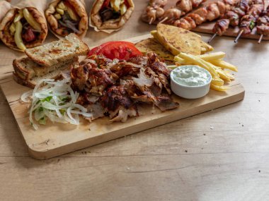 Gyro Greek geleneksel sokak yemekleri dilimledi. Etnik yemek, pide ekmeği, tzatziki yoğurtlu patates ve soğan ahşap masada.