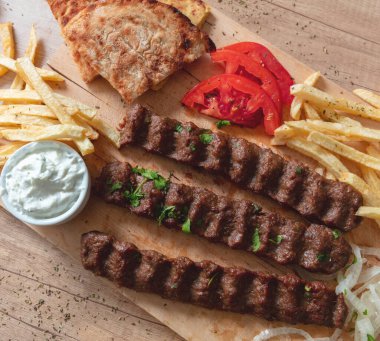 Kebap, donör souvlaki, kavrulmuş et geleneksel sokak yemekleri. Etnik yemek, pide ekmeği, tzatziki yoğurt patates ve soğan ahşap masa, üst manzara