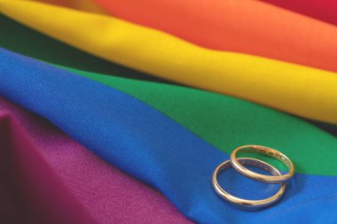 LGBT Gay evliliği. Gökkuşağı renginde, kırışıklıkları olan bir çift altın yüzük, yakın görüş. Boşluğu kopyala.