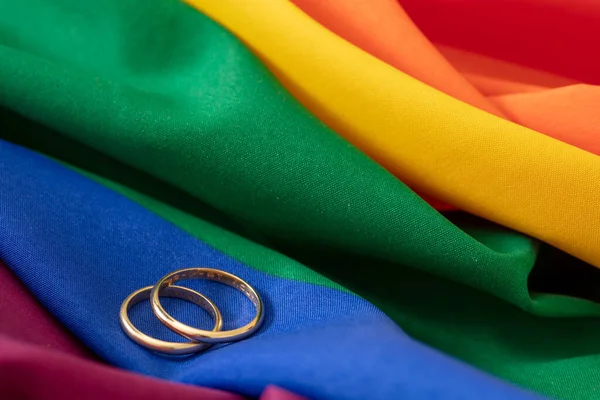 LGBT Gay evliliği. Gökkuşağı renginde, kırışıklıkları olan bir çift altın yüzük, yakın görüş. Boşluğu kopyala.