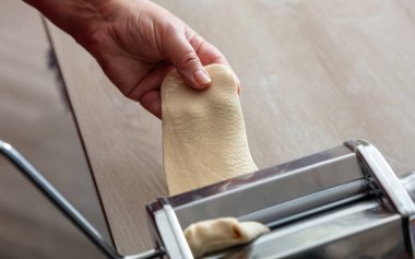 Makarna makinesi. Taze makarna, ev yapımı. Erkek el hamur fileto yapıyor. Yakın görüş.