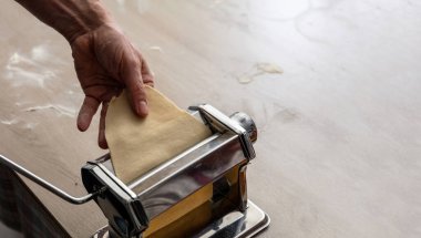 Makarna makinesi. Taze makarna, ev yapımı. Erkek el hamur fileto yapıyor. Yakın görüş.