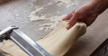 Makarna makinesi. Taze makarna, ev yapımı. Erkek el hamur fileto yapıyor. Yakın görüş.