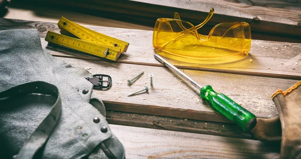 Ahşap arka planda iş aleti ve güvenlik teçhizatı kullanılmış. İnşaat endüstrisi. El aletleri eski ahşap, marangozluk vintage ekipmanları.