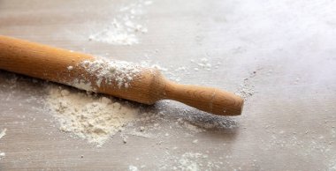 Mutfak masasında ev yapımı hamur ve pasta hazırlığı. Yuvarlanan iğne, ahşap hamur silindiri ve un, yakın görüş, boşluğu kopyala