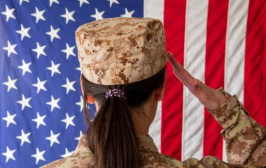 Amerikan bayrağının önünde duran ve selam veren Amerikan askeri kadın. Askeri üniformalı kadın dikiz aynası.