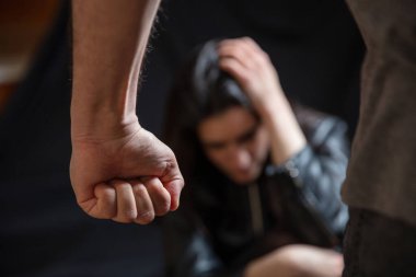 Kadın istismarı, genç bir kadın elleriyle başını tutmaktan korkuyor, erkek yumruğunu sıkıca kavrıyor. Aile içi şiddet, koca eşe karşı. Karanlık oda geri homurdanıyor