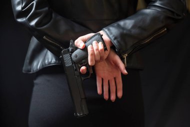 Kadın gizli polis ajanı, katil ya da silah saklayan bir casus. Siyah deri ceketli bir kadın elinde bir silah tutuyor..