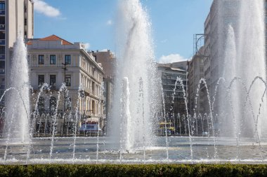 Omonoia Meydanı 'ndaki çeşme, Atina, Yunanistan. Güneşli bir gün, mavi gökyüzü. Omonia şehir merkezinde yuvarlak bir plazadır.