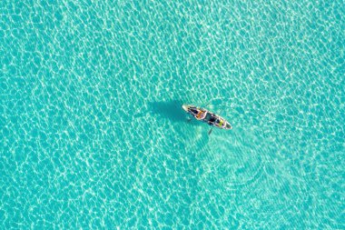 Kano kanosu sonsuz berrak turkuaz mavi şeffaf Ege Denizi 'nde, hava aracı üst görüşü. Yaz tatili eğlencesi, rahatlama ve spor aktivitesi.