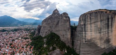 Meteora Yunanistan. Mavi gökyüzü, kayaların üstündeki manastır binaları ve Kalambaka kasabası ve vadisi üzerindeki bulutlarla dolu. Avrupa 'da seyahat hedefi