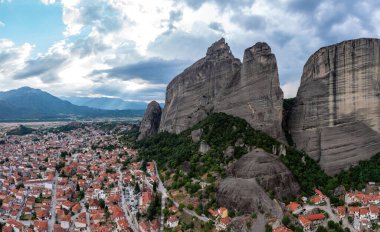 Meteora Yunanistan. Mavi gökyüzü, kayaların üstündeki manastır binaları ve Kalambaka kasabası ve vadisi üzerindeki bulutlarla dolu. Avrupa 'da seyahat hedefi