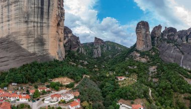 Meteora Yunanistan. Mavi gökyüzü, kayaların üstündeki manastır binaları ve Kalambaka kasabası ve vadisi üzerindeki bulutlarla dolu. Avrupa 'da seyahat hedefi