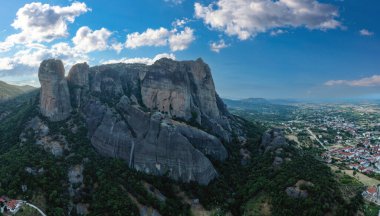Güneş doğarken meteora Yunanistan, kayaların tepesindeki Manastır binaları ve Kalambaka kasabası ve vadisi üzerindeki bulutlarla mavi gökyüzü. Avrupa 'da seyahat hedefi