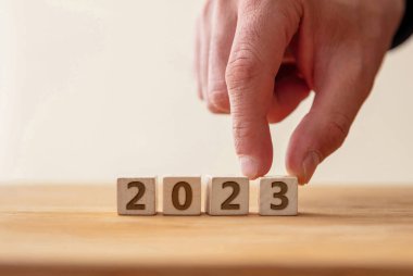 2023 Mutlu Yıllar Kutlama Konsepti. Tahta küpte 2023 numara, 3 haneli rakamlara parmak basmak için. Yeni plan, iş, kariyer, hedef, başarı. Tebrik kartı.