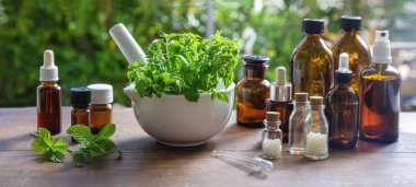 Bitkisel ilaçlar, alternatif şifa. Doğa eczanesi ve homeopati ürünleri. Havanda taze bitkiler, tahta masada cam şişeler, pankart..
