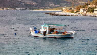 Mani Laconia, Peloponnese. Sakin denizde demirli bir balıkçı teknesi, deniz kenarında bir ev kayalık arazide harabe bina, güneşli bir gün. Yunanistan 'da yaz tatili.