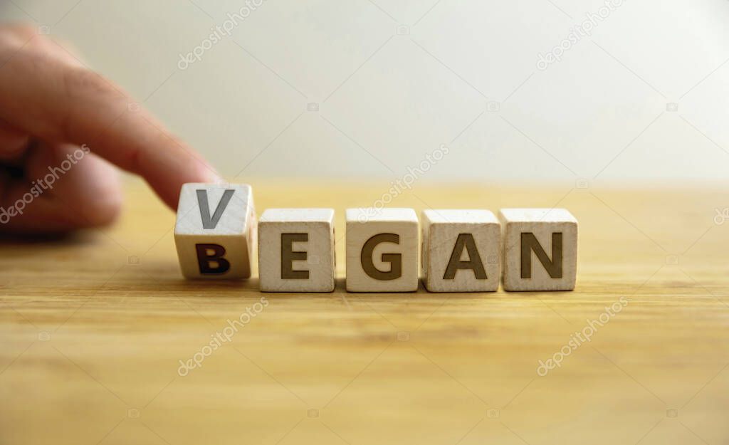 Began vegan lifestyle concept. Finger flips letter at wooden cube changing the word began to vegan. Message for starting healthy food, nutrition, diet without animal and its product.