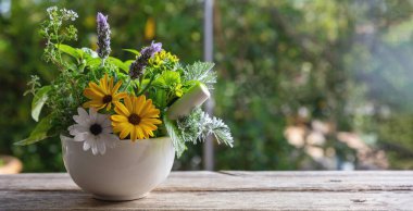 Fresh herbs in a mortar, herbal medicine, alternative healing. Mint, rosemary, basil and lavender aromatic leaves, on a wooden table, copy space