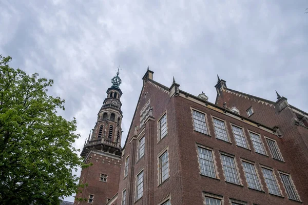 Leiden City Hall building. Renaissance rhythm Town Hall with red brick wall and clock tower, Holland Netherlands. Cloudy sky background. Under view