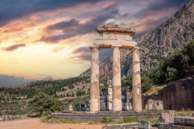 Delphi Yunanistan, Arkeoloji Bölgesi. Antik Yunan tapınak taşı ve sütunlar harabeler, günbatımı arka planında bulutlu gökyüzü