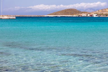 Kythera port Ionian islands, Greece. View of Kithira harbor from the ship, transparent calm infinite sea, seaside building, boat, hill, blue sky background. Summer destination.