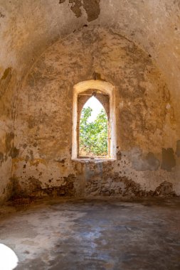 Kithira Kastro of Milopotamos Kato Chora Ionian islands, Greece. Interior view of green tree from ruined building window at old stonewall Venetian castle. Vertical