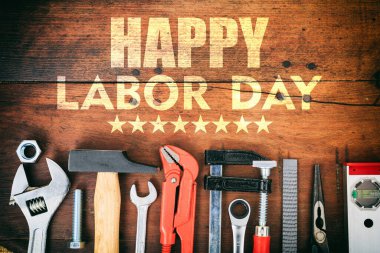 Happy Labor Day text and construction tools on wooden table, top view. United States America holiday celebration