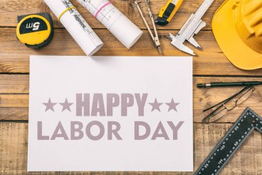 Happy Labor Day text and construction tools on wooden table, top view. United States America holiday celebration