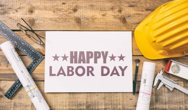 Happy Labor Day text and construction tools on wooden table, top view. United States America holiday celebration
