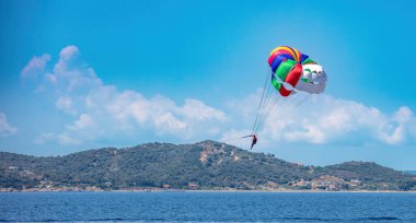 Parachute extreme sport in the sky over sea water. Active woman fly over rippled water, parasailing in Greece near coast