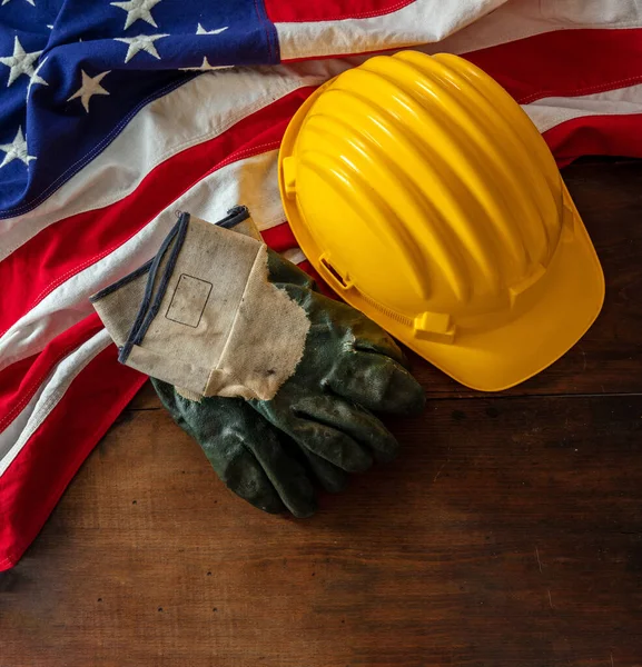 Labor day. Construction helmet and USA Flag on wood, top view, copy space. US holiday celebration