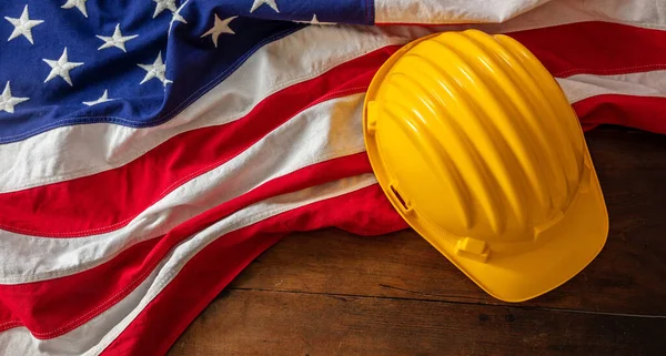 Labor day. Construction helmet and USA Flag on wood, top view. US holiday celebration