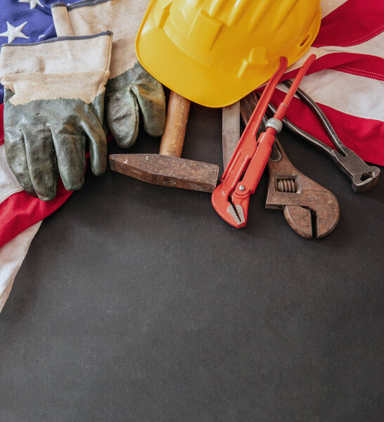 Концепция Дня труда. Американский флаг и строительные инструменты на темном фоне, вид сверху. Праздник США