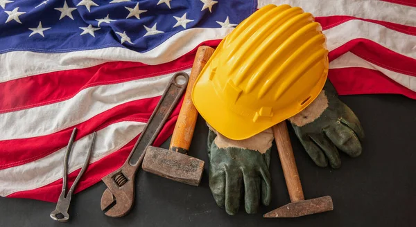 Labor Day concept. American flag and construction tools on dark background, above view. USA holiday celebration