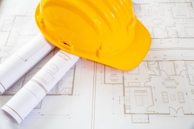 Construction project. Yellow safety helmet and building blueprint plans, copy space. Architect engineer office