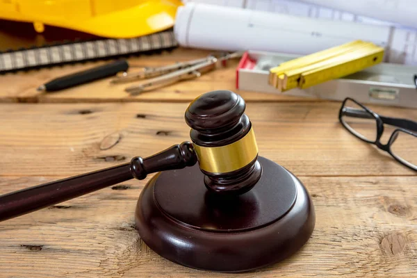 Construction and Labor law. Judge gavel and engineering tools on wooden table, close up view.