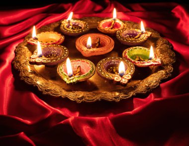 Happy Diwali. Diya oil lamps lit on red color background, close up above view. Deepavali celebration. Hindu Festival of light