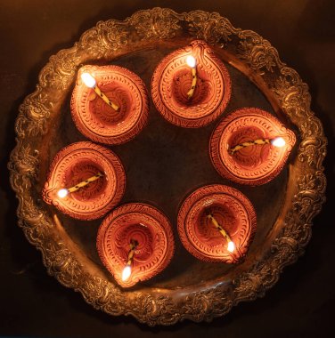 Deepavali Diwali, Hindu Festival of lights celebration. Diya oil lamp lit on traditional Puja thali, top view.