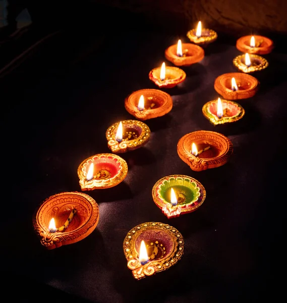 Diwali. Deepavali Hindu festival of lights. Clay diya candles in rows. Oil lamp lit on dark backgroun