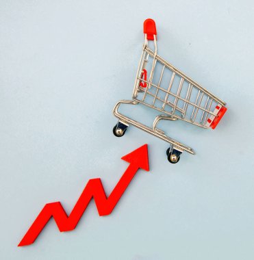 Market fiyatları arttı, gıda fiyatları arttı. Alışveriş arabası ve kırmızı ok. Mali kriz ve enflasyon kavramı.